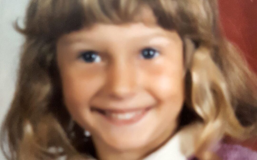 Petra Brigitte als Kind mit kinnlangen blonden Haaren und mit strahlenden Augen und einem hübschen Lächeln.